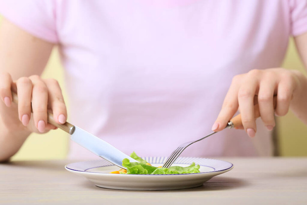 Woman eating vegetables at table, closeup. Concept of anorexia - Foto, afbeelding