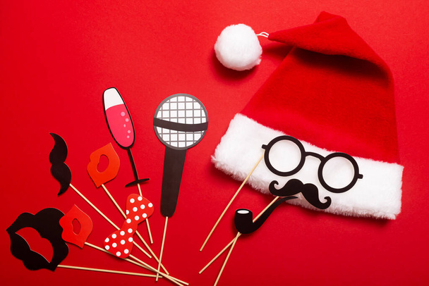 サンタの帽子とメガネと口ひげと喫煙パイプからの顔を持つ赤い色のバナー。新年会やカラオケパーティーなどでお客様を楽しませるための小道具. - 写真・画像