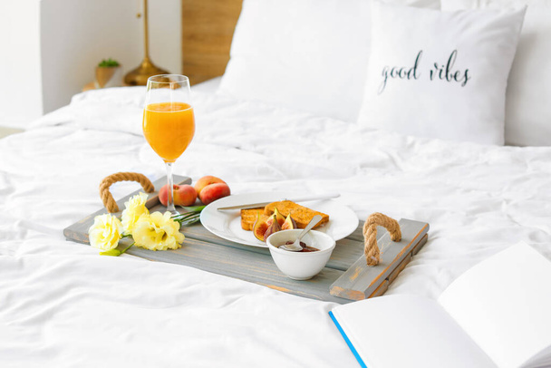 Tray with tasty breakfast and book on bed - Foto, Imagem