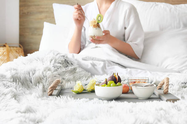 Mujer joven desayunando sabroso en la cama - Foto, Imagen