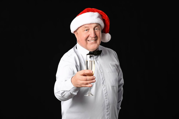 Homme âgé avec champagne célébrant Noël sur fond sombre - Photo, image