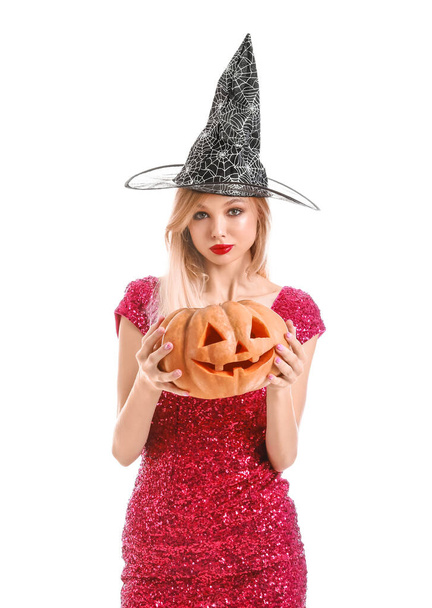 Beautiful young witch with Halloween pumpkin on white background - Photo, image