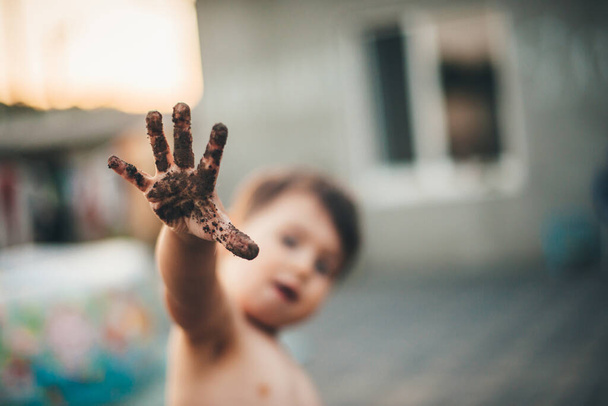 Роздягнений на Кавказі хлопець з брудною рукою грається надворі і веселиться в літній день. - Фото, зображення