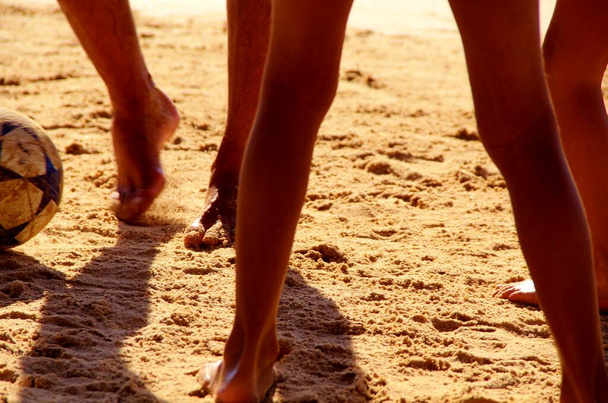 Zicht op mensen benen voetballen op het zandstrand  - Foto, afbeelding