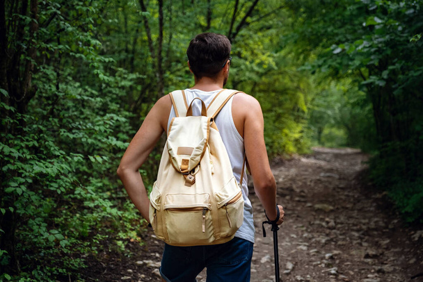 Portrait of a man hiker walking on the trail in the woods. Strong sporty traveling male with backpack on a forest background. - Fotografie, Obrázek