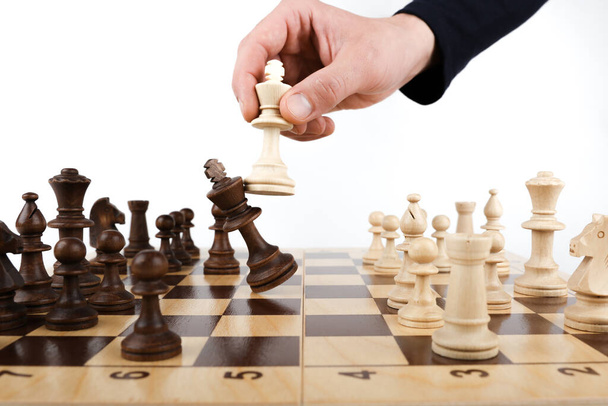 hand holds a chess king piece and defeats another king close up - Foto, imagen