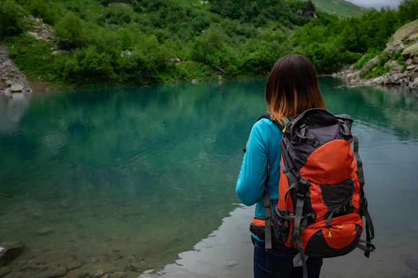 El viajero mira el lago de la montaña. Viajes y concepto de vida activa. Aventura y senderismo en la región de las montañas en el Cáucaso Norte, Dombai, RusiaCáucaso Norte, Dombai, Rusia - Foto, imagen