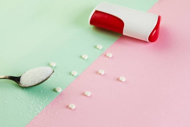 Sugar substitute tablets and natural sweetener powder on a green-pink background. - Photo, image
