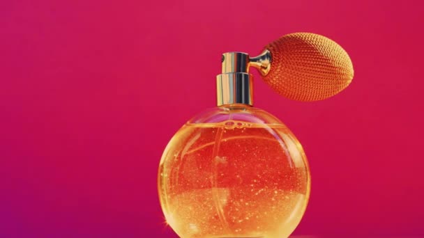 Золотая бутылка аромата и сияющие светлые вспышки на розовом фоне, гламурный аромат духов как праздничный парфюмерный продукт для косметической и косметической марки - Кадры, видео