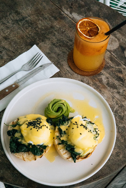 Top view of Healthy Breakfast with Bread Toast and Poached Egg with spinach, avocado on wooden table and orange smoothie on the background - Fotó, kép