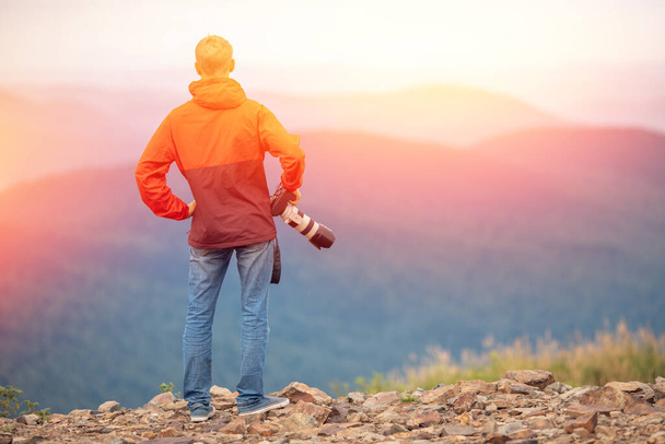 Φωτογράφος άνθρωπος θαυμάζει ηλιοβασιλέματα, επιτυχής παίρνει φωτογραφία σε περιοδεία με την κάμερα, πίσω όψη - Φωτογραφία, εικόνα