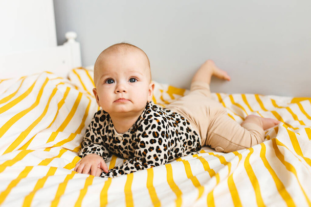 Happy baby with cute smile sitting in a cot. Child sitting in the bed. Happy childhood. - Foto, imagen
