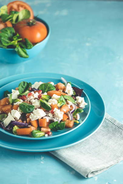Sininen lautanen tuoretta superruokaa terveellistä salaattia punasipulia, tomaatteja, doucette (karitsasalaattia, maissisalaattia, peltosalaattia) ja fetajuustoa. Vaaleansininen pinta - Valokuva, kuva