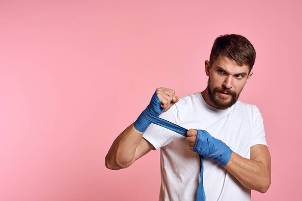 Sportovní muž v bílém tričku boxerské obvazy na rukou cvičení životní styl růžové pozadí - Fotografie, Obrázek