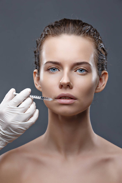 The doctor cosmetologist makes the Rejuvenating facial injections procedure for tightening and smoothing wrinkles on the face skin of a women in a beauty salon. Cosmetology skin care - Valokuva, kuva
