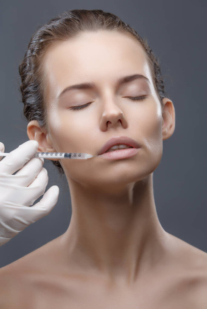 The doctor cosmetologist makes the Rejuvenating facial injections procedure for tightening and smoothing wrinkles on the face skin of a women in a beauty salon. Cosmetology skin care - Photo, Image