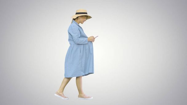 Young pregnant woman in trendy hat walking and using her phone o - Fotoğraf, Görsel