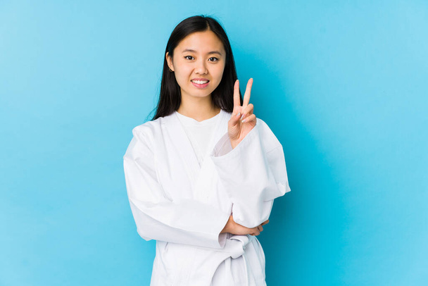 Young chinese woman practicing karate isolated showing number two with fingers. - Foto, immagini