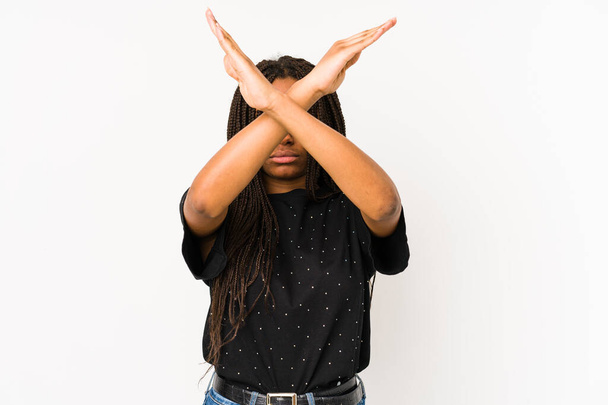 Νεαρή Αφρο-Αμερικανίδα, απομονωμένη σε λευκό φόντο κρατώντας σταυρωμένα τα χέρια, αρνούμενη την ιδέα.. - Φωτογραφία, εικόνα