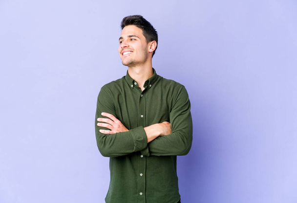 Young caucasian man isolated on purple background smiling confident with crossed arms. - Photo, Image