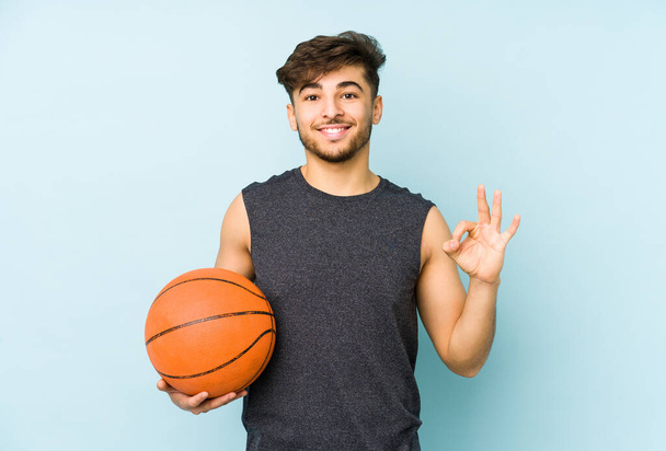 Young arabian man playing basket isolated cheerful and confident showing ok gesture. - Photo, Image
