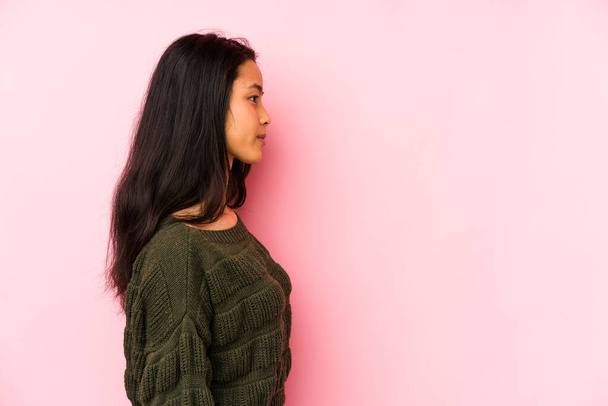 Молодая китаянка изолирована на розовом фоне глядя влево, боком поза. - Фото, изображение
