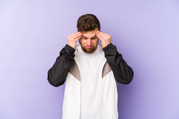 Mladý muž izolovaný na fialovém pozadí dotýkat spánků a mají bolesti hlavy. - Fotografie, Obrázek
