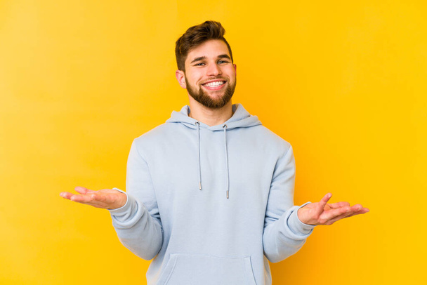 Young caucasian man isolated on yellow background showing a welcome expression. - Photo, Image