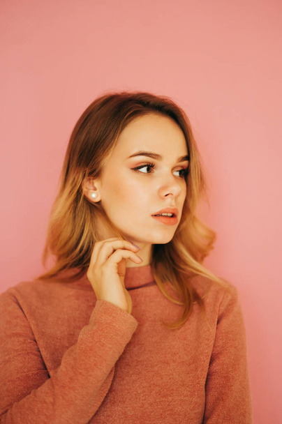 Close vertical portrait of a cute lady in a sweater looking to the side, isolated on a pink background. - Foto, Bild