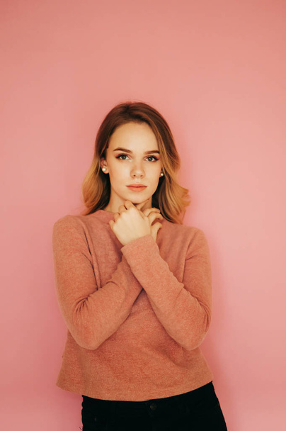 Beautiful young woman standing on a pink background and posing for the camera. Vertical photo. - Valokuva, kuva