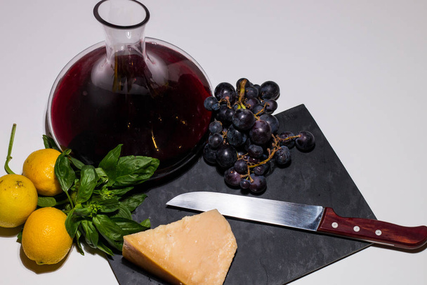 Ελάχιστη διατροφική σύνθεση κρασιού, σταφυλιού και παρμεζάνας (ιταλικό τυρί) σε λευκό φόντο. Φρέσκα φρούτα και τυρί και ένα νόστιμο ιταλικό κρασί. Υγιεινό και παραδοσιακό ιταλικό φαγητό. - Φωτογραφία, εικόνα