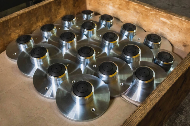 round polished metal workpieces lie in a wooden box at factory in stock - Photo, Image