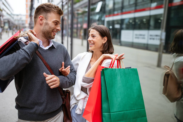 It's shopping and fun time. Cheerful successful happy young lovely couple with shopping bags and laughing - Photo, Image