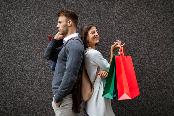 市内に買い物袋を持つ幸せな若いカップル。人々、販売、愛と幸福の概念. - 写真・画像