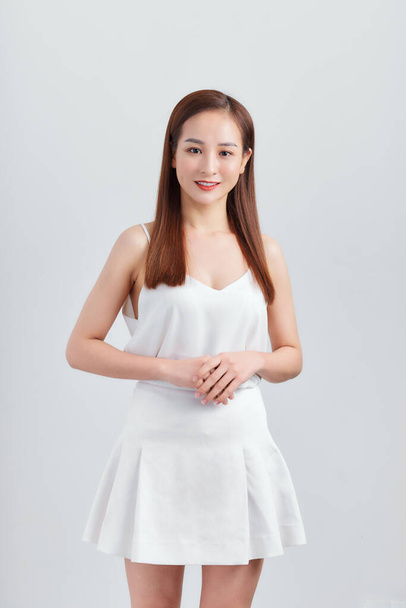 Gyönyörű fiatal szexi nő egy világos szürke ruhát pózol a fehér fal - Fotó, kép