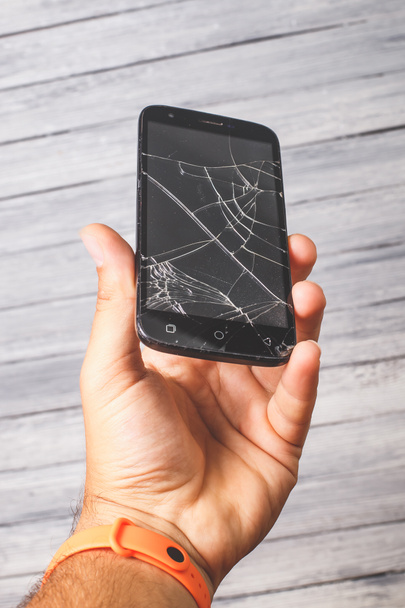 Smartphone preto quebrado na mão em um fundo branco. Foto de estúdio para design - Foto, Imagem