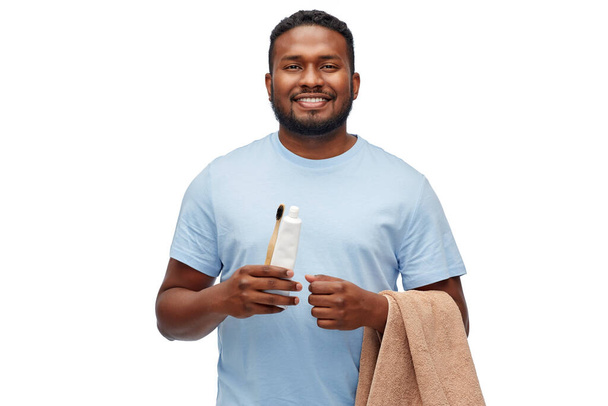 smiling man with toothbrush, toothpaste and towel - Foto, afbeelding
