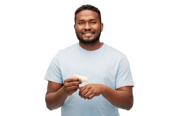 happy african man applying moisturizer to his hand - Фото, изображение