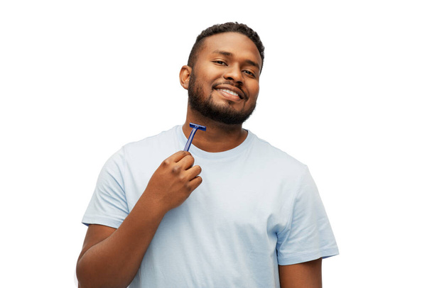 sonriente africano hombre afeitado barba con hoja de afeitar - Foto, imagen