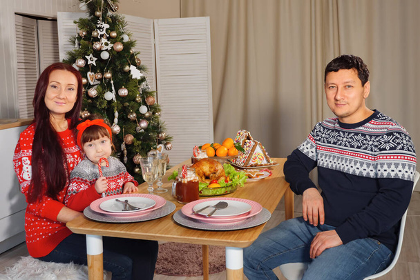 Boldog család az asztalnál a háttérben egy díszített karácsonyfa - Fotó, kép