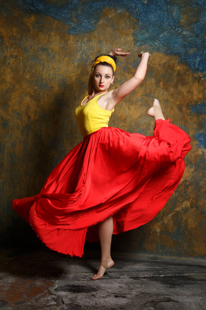 Beautiful girl in a long red skirt is dancing. - Foto, afbeelding
