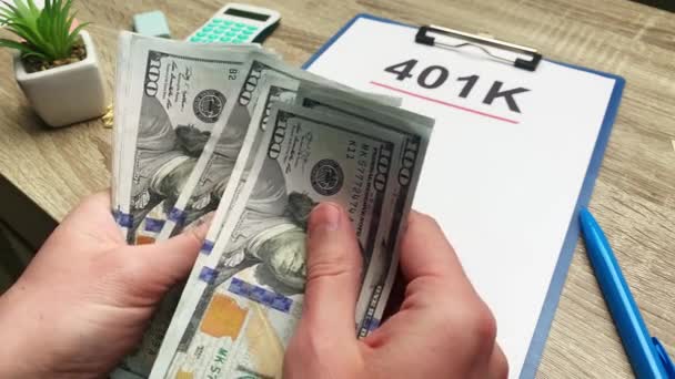 401k pensioen plan, een man telt 100 dollar biljetten aan een houten tafel. - Video