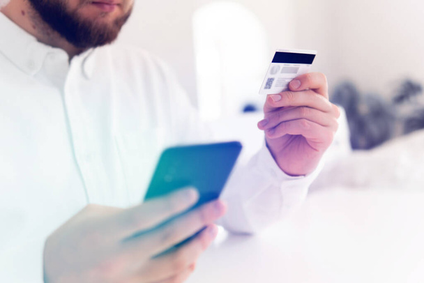 Sulje kädet pitämällä luottokorttia ja käyttämällä mobiili älypuhelin Online ostoksia käsite aamulla valossa. Liikemies kädet käyttämällä älypuhelinta ja pitämällä luottokorttia sosiaalinen - Valokuva, kuva