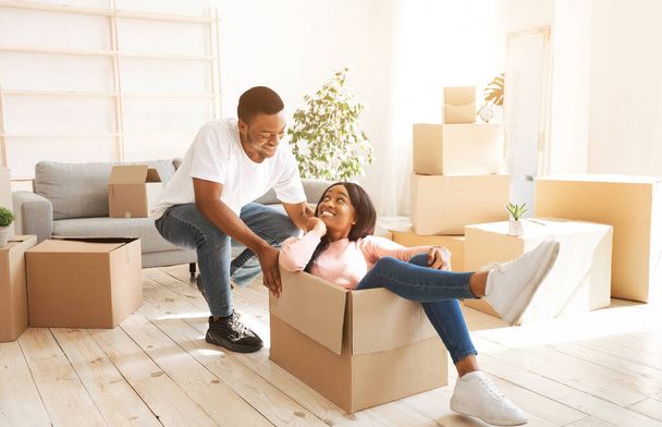 Black woman and her boyfriend playing together with cardboard box during relocation - Foto, Imagem