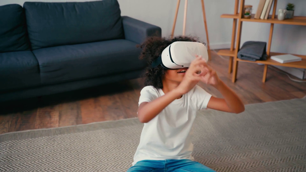 Afrikaans amerikaans meisje dragen vr headset en gebaren, zittend op tapijt  - Video