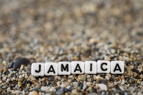 Jamaika-Beschriftungstext mit dem Namen des Urlaubsortes in einem Stillleben der Buchstaben, die auf einem Sandstein am Ufer ausgelegt sind - Foto, Bild