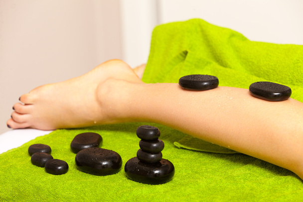 Beauty salon. Woman getting spa hot stone legs massage - Foto, imagen