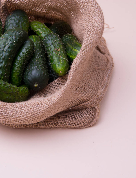 Genç yeşil salatalıklar ahşap bir arka planda bir çantada - Fotoğraf, Görsel