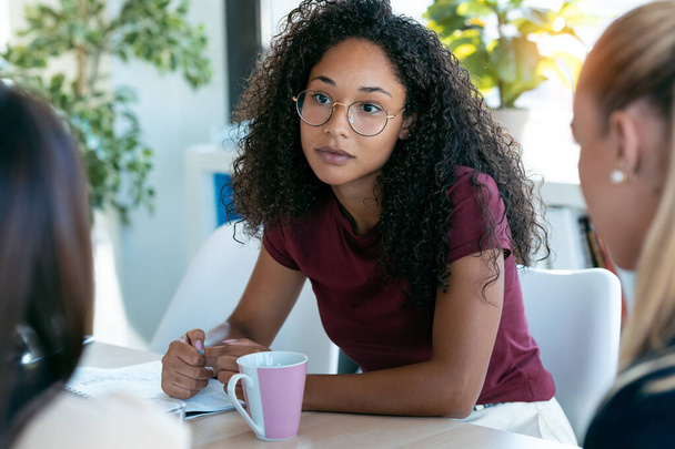 Shot of confident african young business woman listening her partners while working on coworking space. - Φωτογραφία, εικόνα