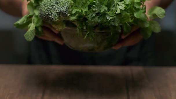 Mužské ruce dát misku zeleně (brokolice, cilantro, máta atd.) na stůl. Zavřít zpomalený pohyb - Záběry, video